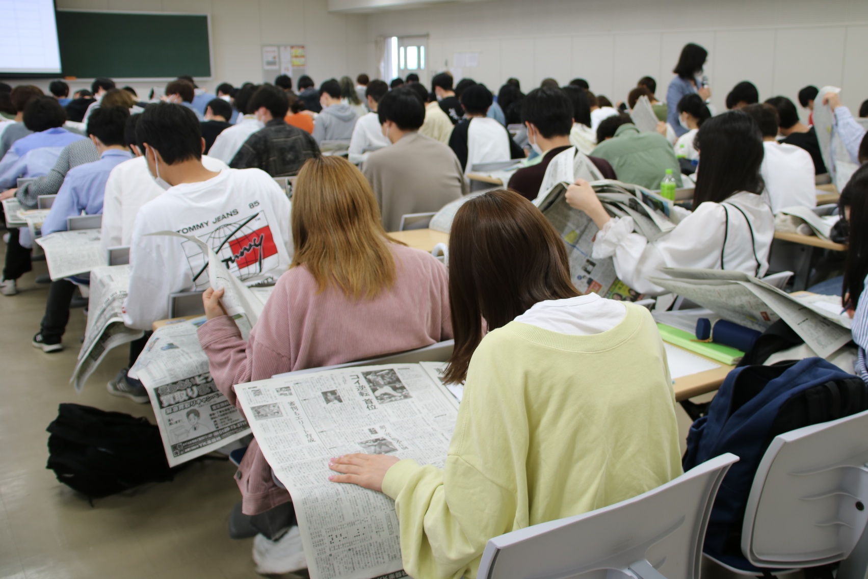 新聞紙面に触れる学生ら